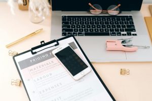 Pricing list on desk next to a laptop